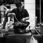 Street food vendor cooking noodles at market