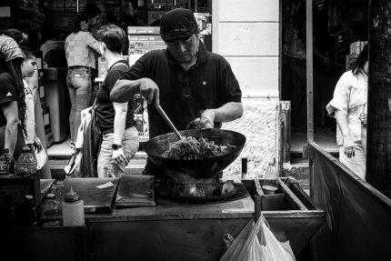 Street food vendor cooking noodles at market